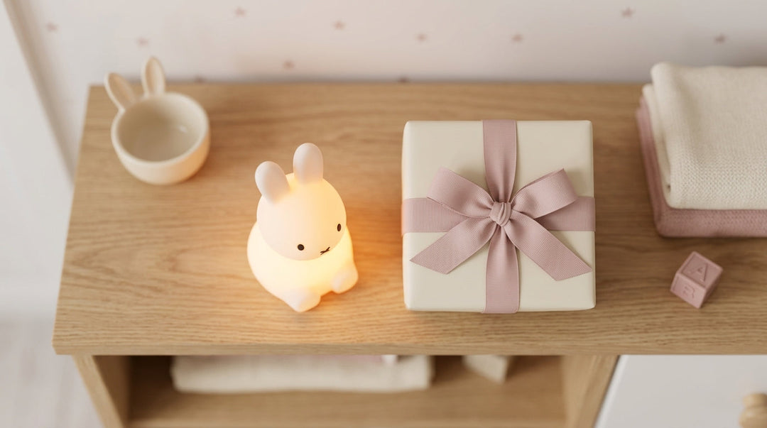 Veilleuse lapin allumée en lumière douce posée près d'un cadeau de naissance emballé